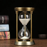 Goldfarbene Sanduhr aus Metall und Glas mit weißem Sand in der Vorderansicht.