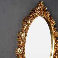 Detailansicht des ornamental verzierten goldfarbenen Rahmens des STEELVIEW Wandspiegels.