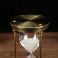 Detailaufnahme der gebürsteten goldfarbenen Metalloberseite der Sanduhr.