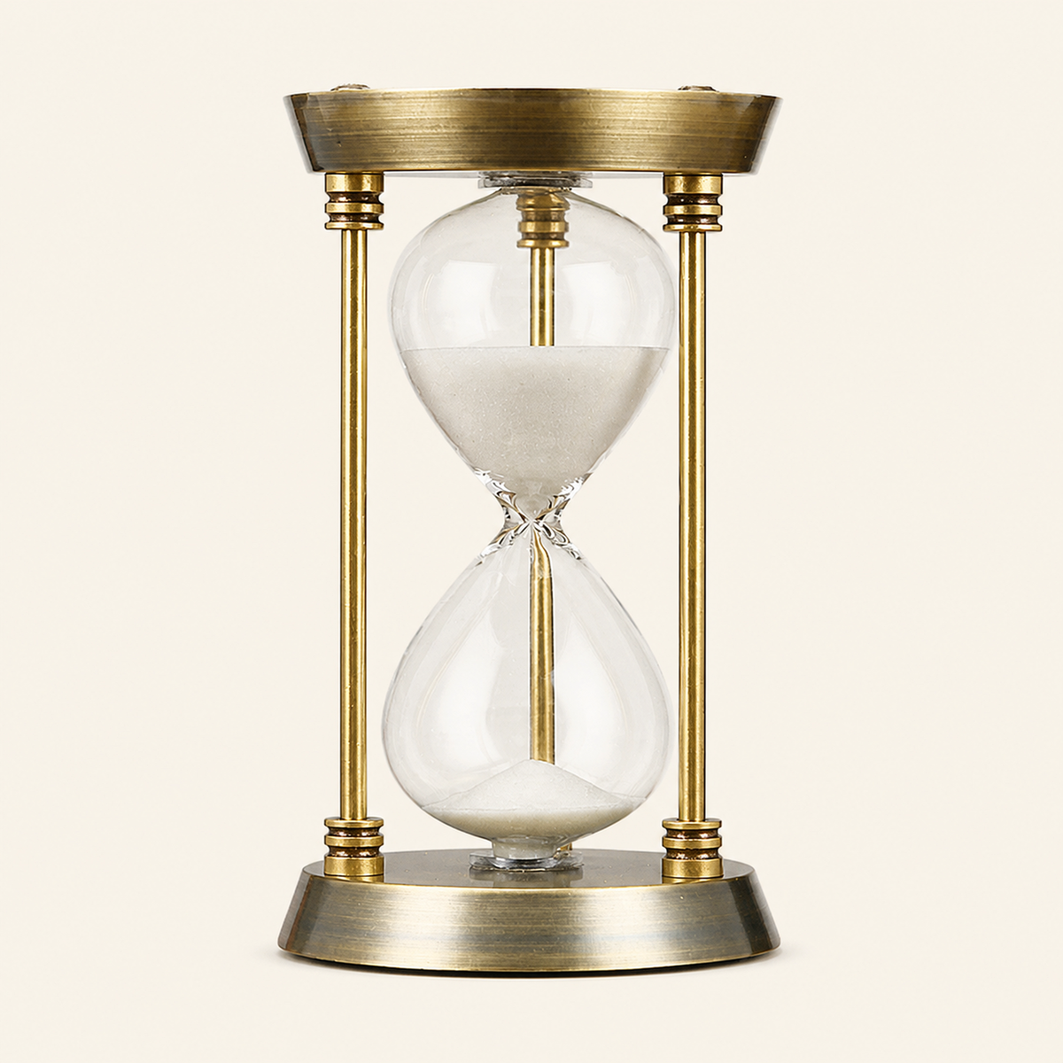 Goldfarbene IRONFORM Sanduhr mit weißem Sand freigestellt auf warmem, neutralem Hintergrund.