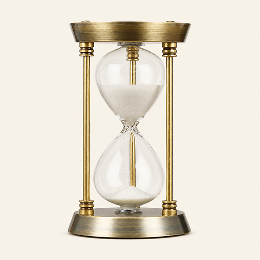 Goldfarbene IRONFORM Sanduhr mit weißem Sand freigestellt auf warmem, neutralem Hintergrund.